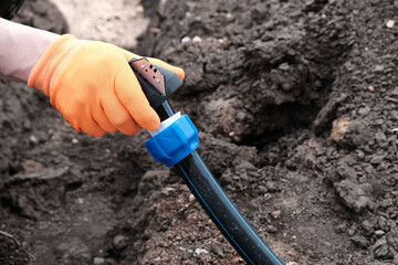 The master installs water supply from HDPE pipes, chamfers the pipe close-up