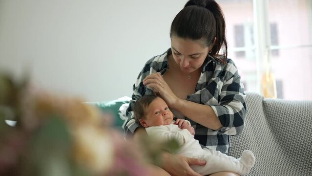 Mother about to breastfeed her baby, preparing herself to give milk to her newborn, sitting on a couch in a cozy home environment with natural light, strong sense of love, care, and maternal bond