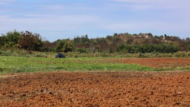 Shot of a farm land with a tracor in the background.