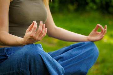 Detail of Young Girl Meditating with Both Hands on Knees in a Natural Green Surrounding
