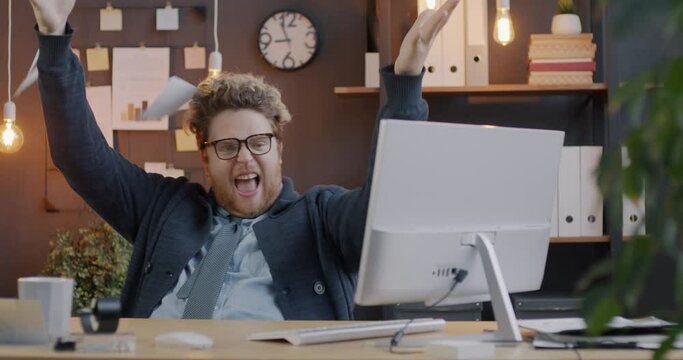 Loop of emotional young businessman tearing paper and throwing it away sitting at desk in office. Business document and emotion concept.