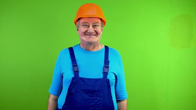 Senior worker in overalls and helmet says yes, nods head and looking at camera.