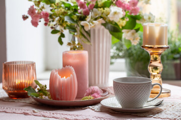 cup of tea with burning candles and pink roses at the window