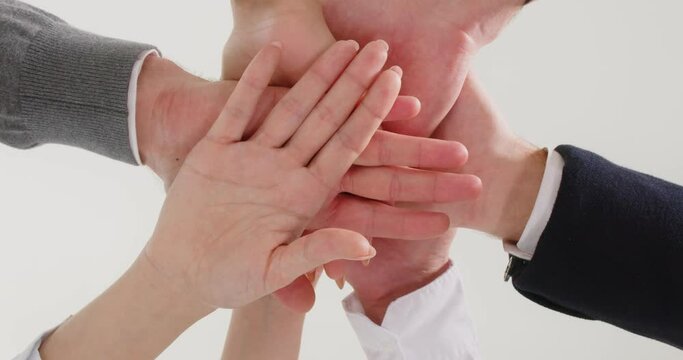 Business team stacking hands. Group of adult people put hands together, rock them up and down, then raise them up in air. View from below. Teamwork, cooperation, support, community, success concept