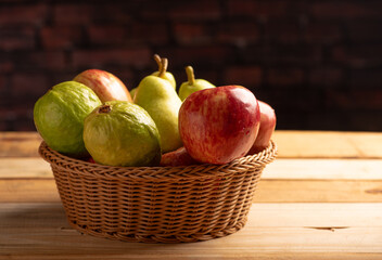Basket with fruits on rustic wooden surface and dark background, selective focus.