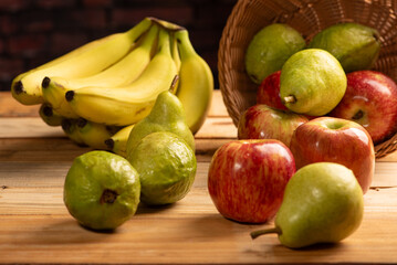 Basket with fruits on rustic wooden surface and dark background, selective focus.