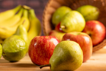 Basket with fruits on rustic wooden surface and dark background, selective focus.