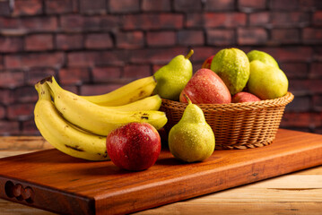 Basket with fruits on rustic wooden surface and dark background, selective focus.