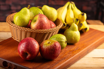 Basket with fruits on rustic wooden surface and dark background, selective focus.
