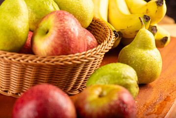 Basket with fruits on rustic wooden surface and dark background, selective focus.
