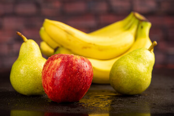 Beautiful fruits placed on dark reflective surface, selective focus.