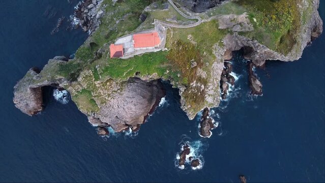 Aerial top view of San Juan de Gaztelugatxe with its hermitage, beaten by the waves of the blue sea. Famous natural and touristic landscape of Biscay, in the Basque Country