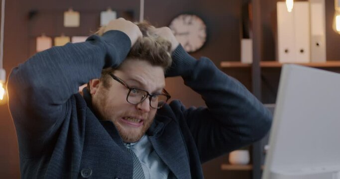 Loop of mad businessperson pulling hair and screaming expressing negative emotion looking at computer screen in office. Crazy businessman and workplace conceept.