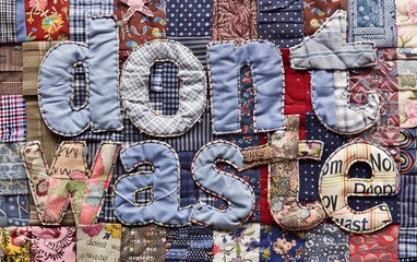 A beautifully crafted patchwork quilt features the words don't waste prominently displayed in large, textured fabric letters