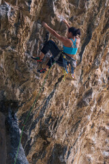 Obraz premium A woman is climbing a rock wall with a green rope. Vertical.