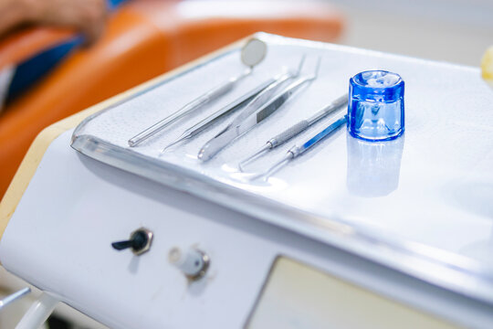 Close-up of dental implements, including: dental mirror, dental explorers, dental tweezers, amalgam carrier, amalgam, resin, cleaning instruments, curettes, scalers