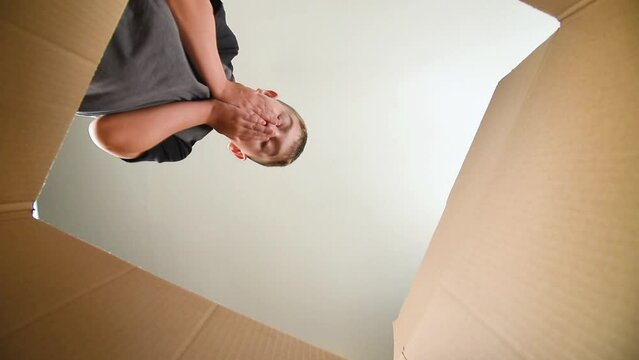 A child is very happy and opening a gift box at home and reaches inside for a Christmas or birthday present unboxing video