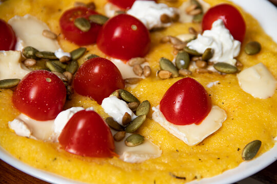 Close-up of cherry tomatoes cheese and seeds on a golden omelette