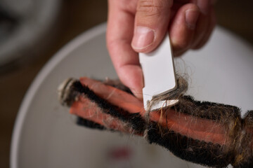 Removing pet fur from a brush and placing it in a bowl as part of grooming routine