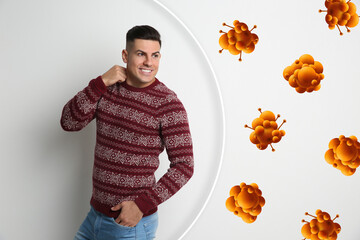 Man with strong immunity surrounded by viruses on light background