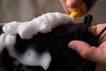 A person is scrubbing a shoe with a sponge and foamy cleaner