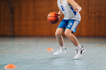 Cropped image of junior basketball player dribbling a ball on training.