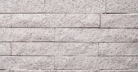 Texture of a natural stone wall made of rectangular blocks as a pink background