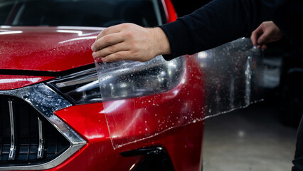 The process of applying protective vinyl film to car headlights in detailing. 