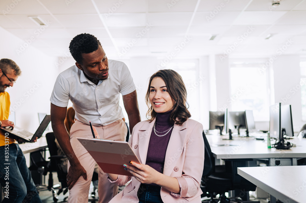 Wall mural Woman with disability discussing marketing strategy with her diverse colleague