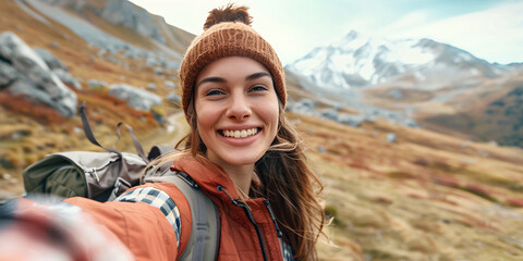 Naklejka premium Woman enjoying her summer vacation in the mountains, taking a selfie and about to go climbing