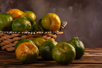 Orange ponkan on rustic wood, black background, selective focus.