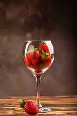 Beautiful crystal glass with strawberries on rustic wood, selective focus.