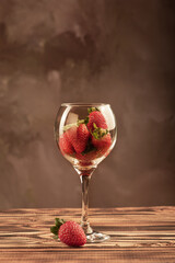 Beautiful crystal glass with strawberries on rustic wood, selective focus.