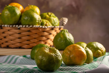 Orange ponkan on rustic wood with green tablecloth, dark background, selective focus.