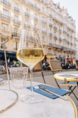 A glass of white wine standing on the table of street cafe in Paris, France. C