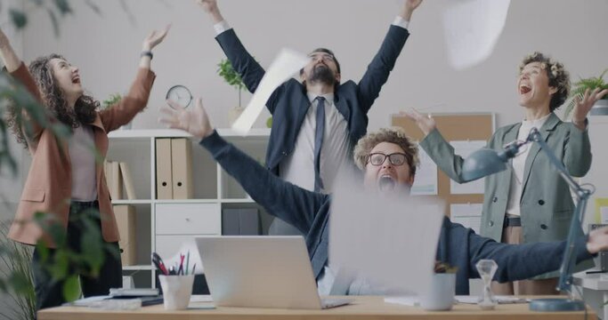 Loop of joyful business people throwing then catching documents laughing enjoying successful project in office. Professional occupation and positive emotion concept.