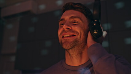 Happy disc jockey creating rhythmic music in nightclub with headphones close up.