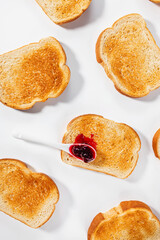 Slices of toasted bread and a spoon of jam lying on one of them, breakfast food