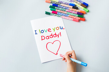 child's hand draws a gift card with felt-tip pens and pencils i love daddy, sweet wish concept...