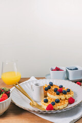 Breakfast with waffles and berries on the wooden table, close-up view