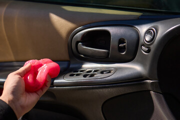 A person is seen holding a pink object near the air vent of a car