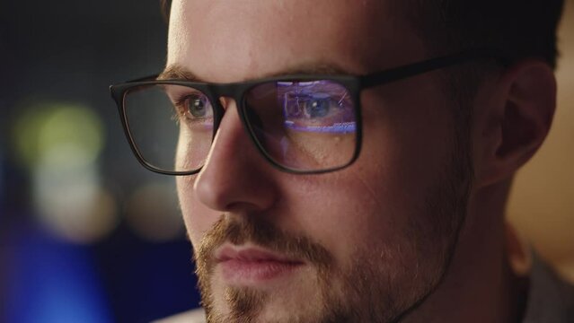 Close up shot of man wearing glasses watching news. Reflection in eyeglasses russian aggression against Ukraine. First cadres in mass media about ukrainian crisis