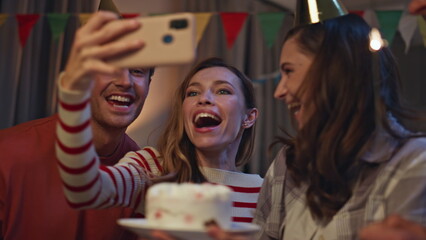 Fototapeta premium Group taking photo birthday party on smartphone close up. People making selfie