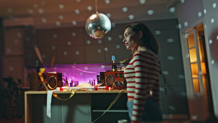 Carefree girl dancing alone after night party in apartment. Lady listening music