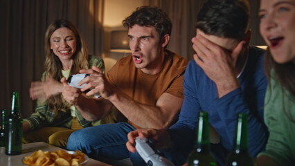 Video gamers have fun playing together at night home close up. Emotional guy 