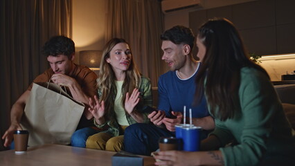 Group millennials chilling home unpacking food delivery on evening gathering.