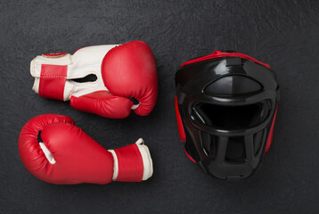 Boxing helmet and gloves on concrete background, top view.