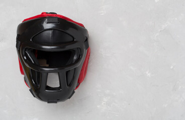Black leather boxing helmet on concrete background, top view.