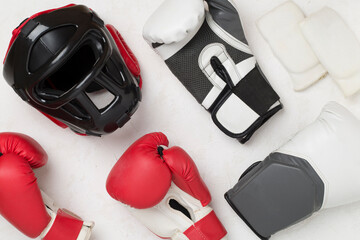 Boxing helmet and gloves on color background, top view