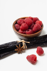 Vanilla beans with raspberries on white background